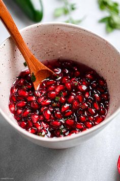 a bowl filled with pomegranate and a wooden spoon sitting in the bowl