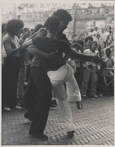 two people are dancing in front of a crowd with their arms wrapped around each other