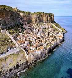 an aerial view of a small village on the edge of a cliff by the ocean