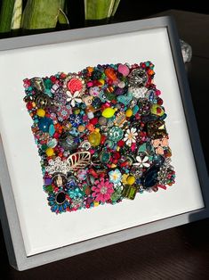 a white frame holding a bunch of assorted beads and brooches on it