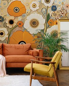 an orange couch sitting in front of a wall with flowers on it and a mirror