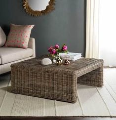 a wicker coffee table with pink flowers on it in front of a blue wall