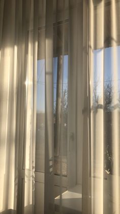 an open window with white curtains and the sun shining through it's glass panes