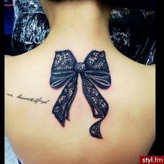 the back of a woman's neck with a bow tattoo