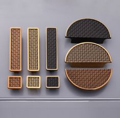 four pieces of gold and black brooches on a gray surface, including one with an intricate design