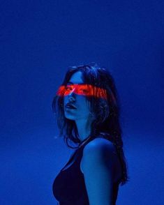 a woman with red glasses on her face standing in front of a dark blue background