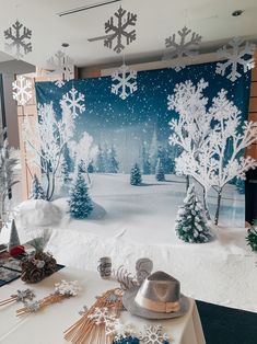 a snow scene is displayed on the wall behind a table with decorations and other items