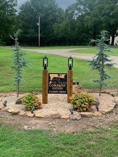 a sign in the middle of a park with trees around it and grass on both sides