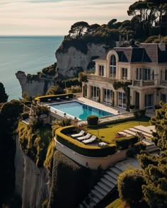 an aerial view of a large house with a swimming pool in front of the ocean