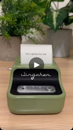 an old fashioned typewriter sitting on top of a wooden table next to a potted plant