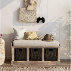 a white bench with baskets underneath it and a hat hanging on the wall behind it