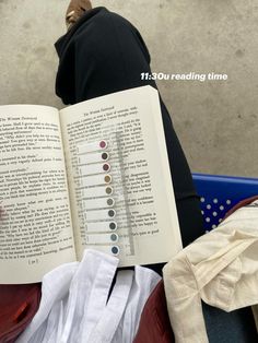 an open book sitting on top of a pile of clothes