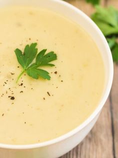 a white bowl filled with soup and garnished with parsley on the top