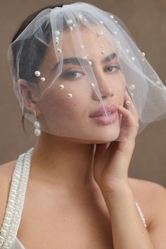 a woman wearing a veil with pearls on it