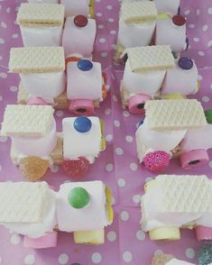 small cakes made to look like cars and trucks on pink paper with white polka dots