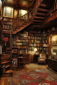 a room with stairs, bookshelves and rugs on the wooden flooring