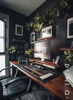 a desk with a monitor, keyboard and phone on it in front of a window