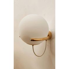 a wall light with a white glass ball on the back and gold trim around it