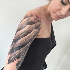 a woman with a black and grey feather tattoo on her arm