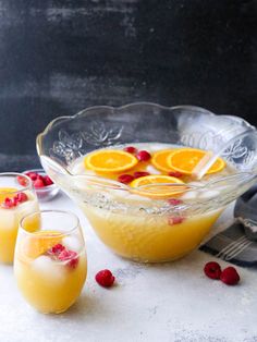 three glasses filled with orange juice and garnished with raspberries on a table