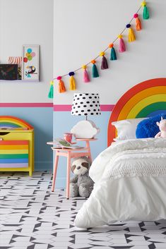 a child's bedroom decorated in bright colors with rainbows and pom poms