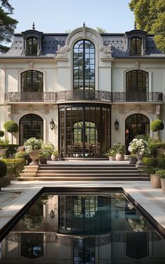 a large white house with lots of windows and plants in front of the pool area