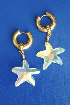 Bring star-studded glamour to your look with these Emmeline Earrings. Featuring eye-catching iridescent stars, these earrings will make you feel like an alluring #SeliniStar! Take your outfit to the next level with these dazzling earrings and show off your amazing style. Made of Stainless Steel Gold Plated Hoop Earrings and Swarovski Crystals.Size: 1.96 in Made in Greece. Celestial Star-shaped Sparkling Earrings, Elegant Handmade Starfish Earrings, Sparkling Star-shaped Celestial Earrings, Gold Star-shaped Crystal Earrings For Party, Celestial Crystal Earrings For Parties, Star-shaped Crystal Earrings For Party, Trendy Hoop Earrings With Star Charm For Party, Elegant Star-shaped Hoop Earrings For Party, Trendy Party Hoop Earrings With Star Charm