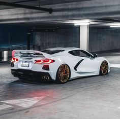 a white sports car parked in an empty parking garage with yellow rims on it