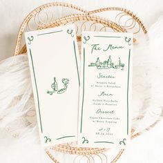 two green and white menu cards sitting on top of a table next to a wicker basket