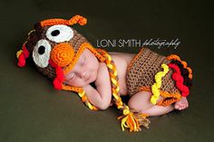 a newborn baby wearing a crocheted turkey hat and diaper cover with orange trim