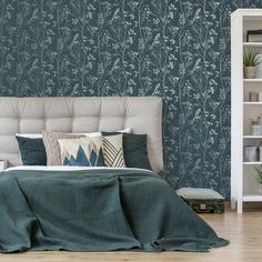 a bedroom with blue wallpaper and green bedding, white bookcases and bookshelves