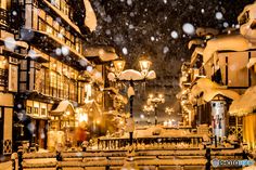 a snowy night in the city with street lights and buildings