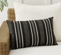 a black and white pillow sitting on top of a bed next to a wicker chair