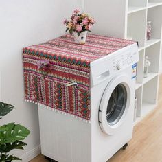 a washer sitting in front of a white wall next to a flower pot on top of a shelf