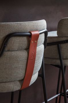 two bar stools with leather straps on each one and the other armrests