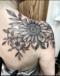 a sunflower tattoo on the back of a woman's shoulder