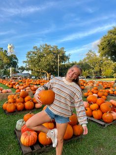 a woman is sitting on some pumpkins in the grass