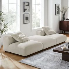 a living room filled with furniture next to two large windows on top of a hard wood floor