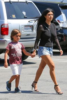 the mother and daughter are walking hand in hand through an airport parking lot with cars behind them