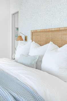 a bed with white sheets and pillows in a bedroom