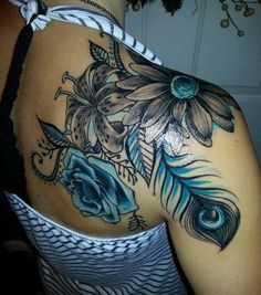 the back of a woman's shoulder with blue flowers and feathers on her arm