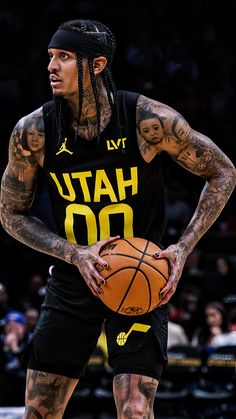 a man with tattoos holding a basketball in his hands