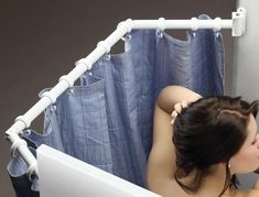 a naked woman sitting in front of a bath tub next to a blue shower curtain