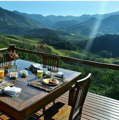 an outdoor table with food and drinks on it in front of the mountain range,