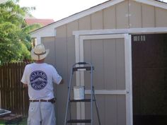 a man standing next to a ladder in front of a shed