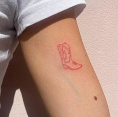 a small tattoo on the arm of a woman with a cowboy boot in red ink