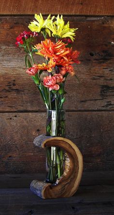 a vase filled with lots of colorful flowers on top of a wooden table next to a wall