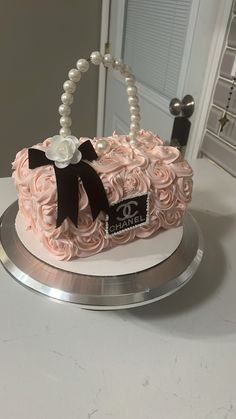 a cake that is on top of a silver platter with pearls and a black bow