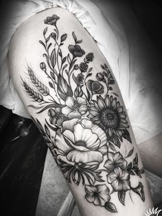 a woman's thigh with flowers and leaves tattooed on her leg, in black and white