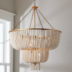 a chandelier with beads hanging from it's sides in front of a window